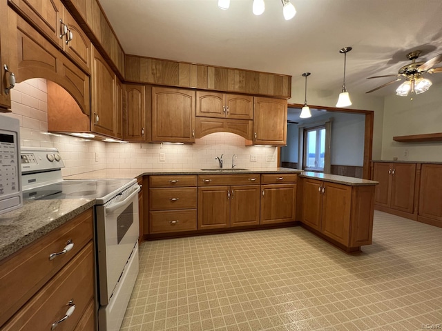 kitchen featuring white range with electric stovetop, brown cabinetry, a peninsula, a sink, and backsplash