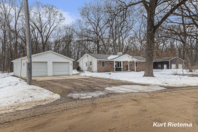 view of front of property featuring a garage, brick siding, an outdoor structure, and a chimney