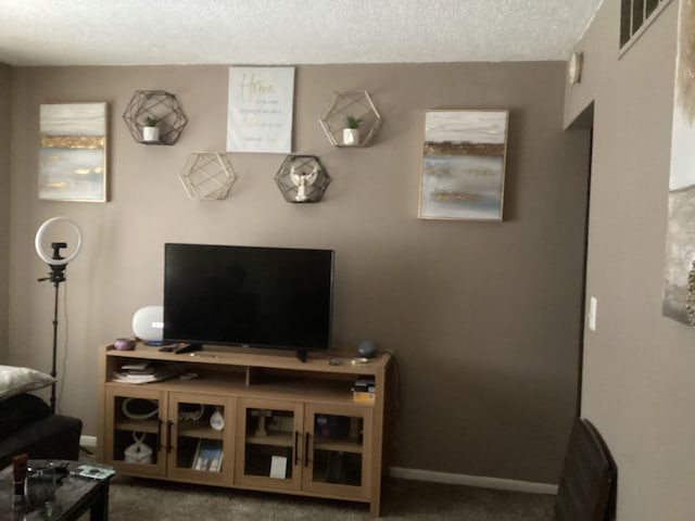 carpeted living room featuring baseboards, visible vents, and a textured ceiling