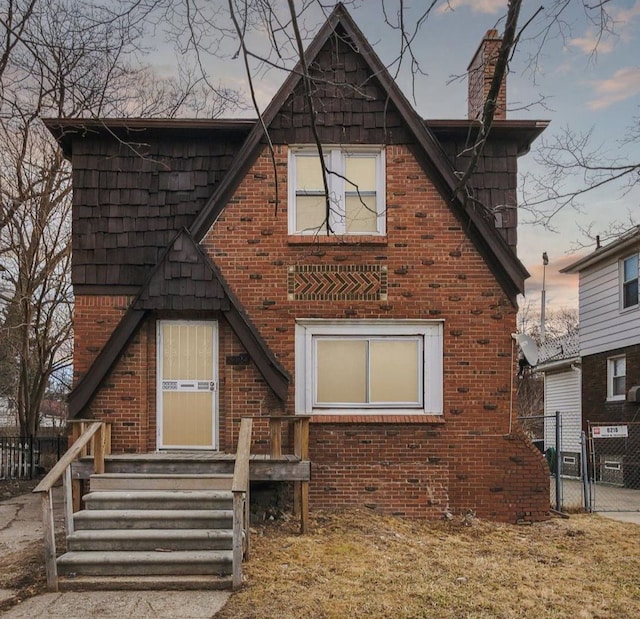 view of front of property featuring a gate, fence, and brick siding