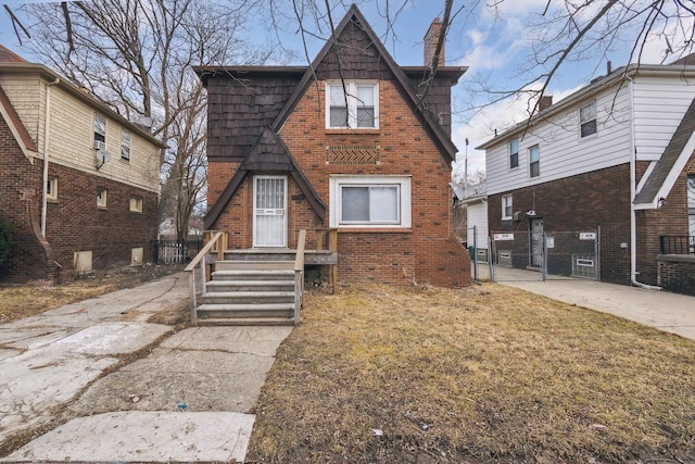 view of front of home featuring brick siding, fence, central AC unit, a chimney, and a gate