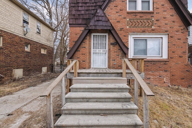 view of exterior entry featuring brick siding and mansard roof