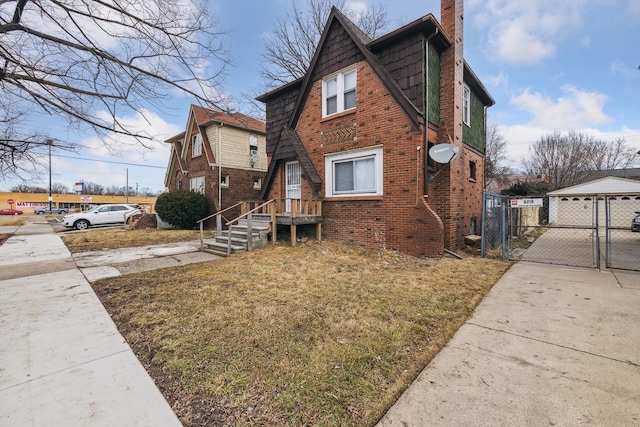 view of side of property featuring a gate, fence, brick siding, and a chimney