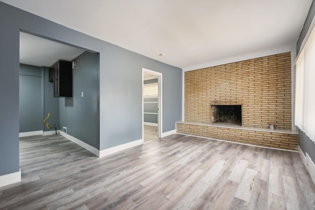 unfurnished living room with baseboards, wood finished floors, and a fireplace