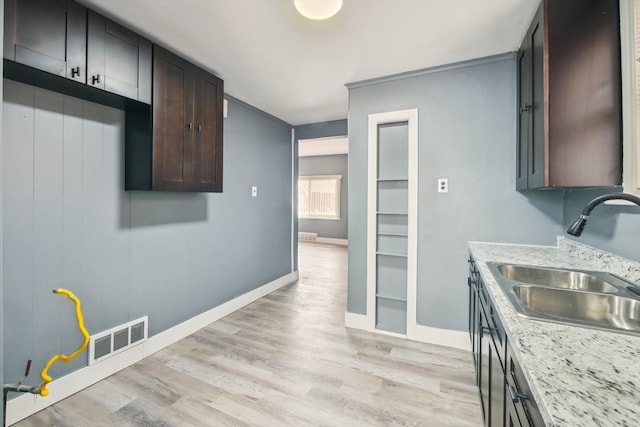 kitchen with visible vents, light wood-style flooring, a sink, baseboards, and dark brown cabinets