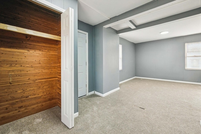 unfurnished bedroom featuring beam ceiling, baseboards, visible vents, and carpet floors