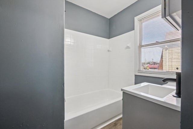 full bath featuring wood finished floors, shower / bathtub combination, and a sink