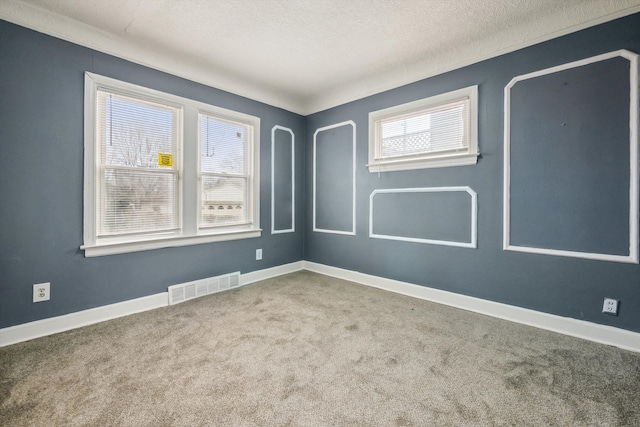 carpeted empty room featuring baseboards, visible vents, and a textured ceiling