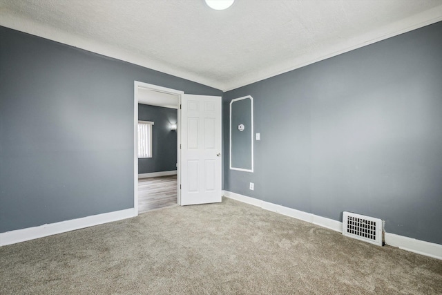 spare room featuring baseboards, visible vents, carpet floors, and a textured ceiling