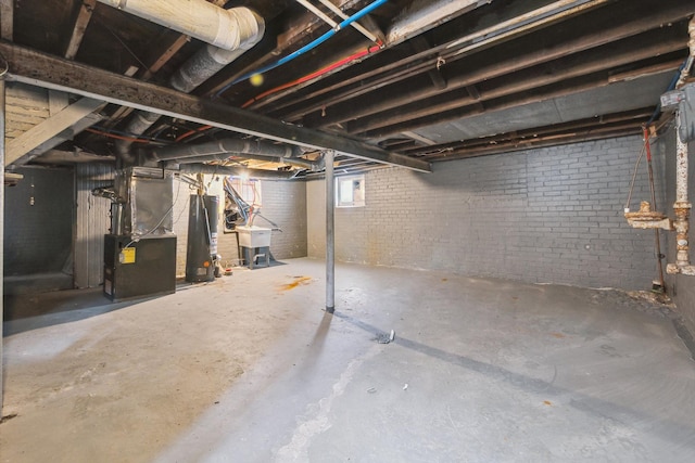 below grade area featuring a sink, heating unit, and brick wall