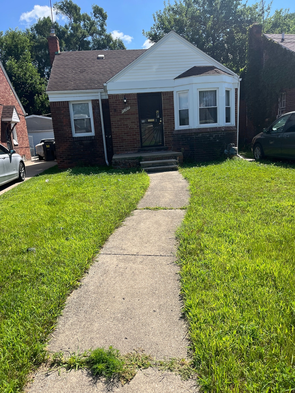 view of front of home featuring brick siding, a chimney, and a front yard