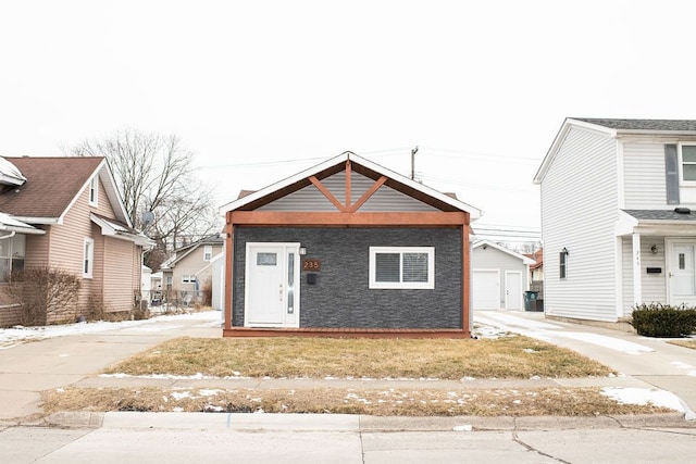 view of front facade featuring driveway, a detached garage, and an outdoor structure