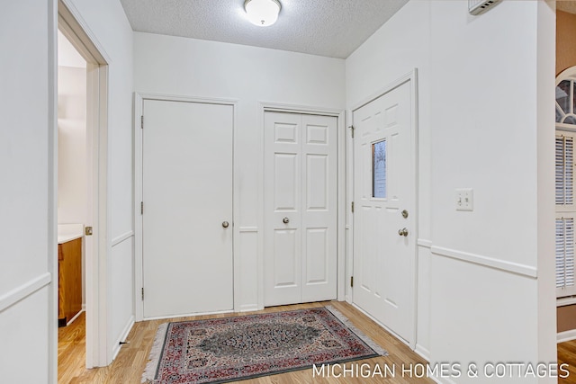 entryway with light wood-type flooring and a textured ceiling