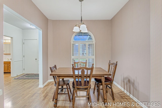 dining space featuring light wood-type flooring, an inviting chandelier, and baseboards