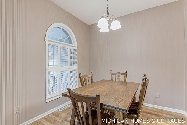 dining space with baseboards, an inviting chandelier, visible vents, and light wood-style floors