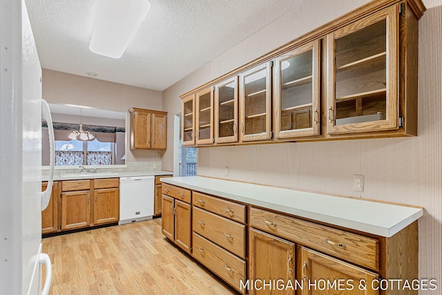 kitchen featuring brown cabinetry, white appliances, light countertops, and light wood-style flooring