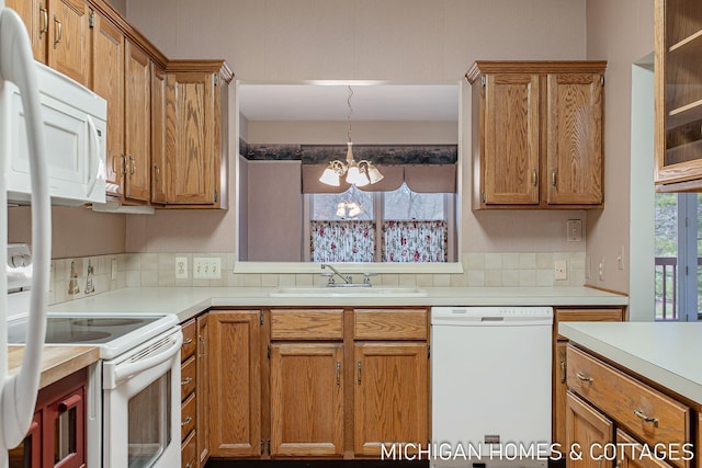 kitchen featuring a chandelier, white appliances, a sink, light countertops, and brown cabinets