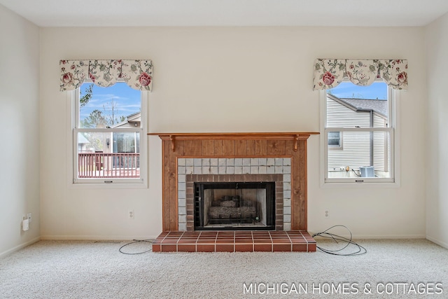 unfurnished living room featuring carpet floors, a tile fireplace, and baseboards