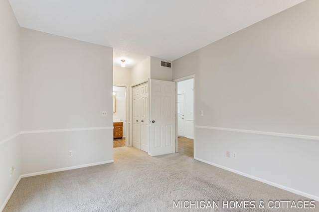 unfurnished bedroom with carpet floors, a closet, visible vents, and baseboards