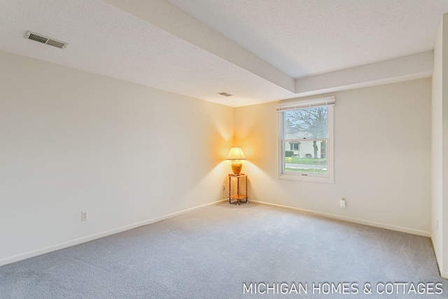 unfurnished room with carpet, visible vents, and a textured ceiling