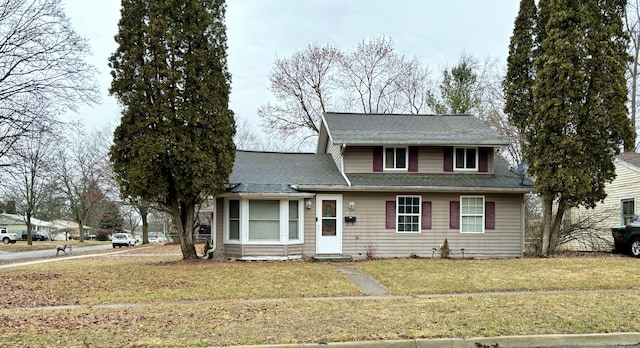 traditional-style house featuring roof with shingles and a front lawn