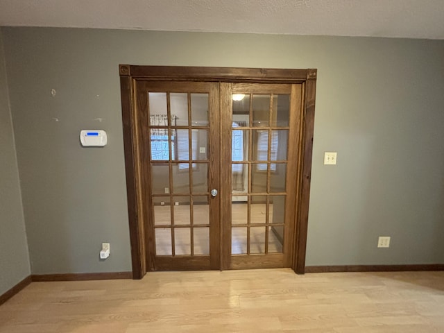 doorway with french doors, baseboards, and wood finished floors