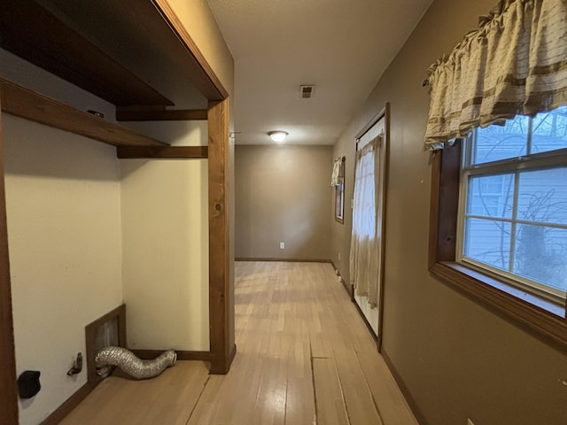 corridor featuring light wood-style floors, baseboards, and visible vents