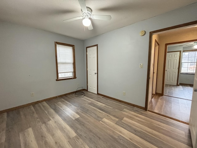 empty room with light wood-style floors, ceiling fan, and baseboards