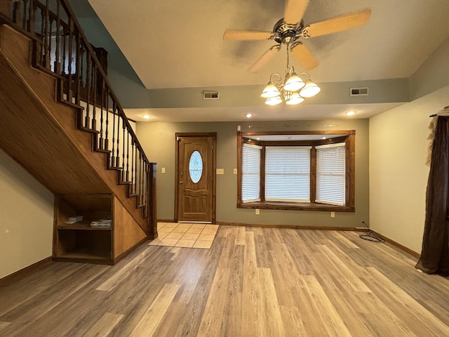 entryway featuring baseboards, visible vents, light wood finished floors, and stairs