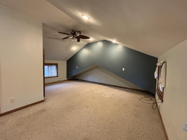 additional living space with lofted ceiling, baseboards, a ceiling fan, and light colored carpet