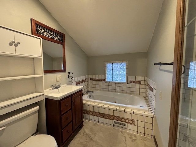 bathroom with visible vents, toilet, vaulted ceiling, vanity, and a tub with jets