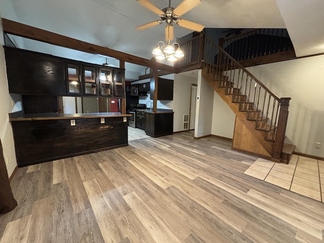 kitchen featuring stainless steel electric range, a sink, light wood-style flooring, and baseboards