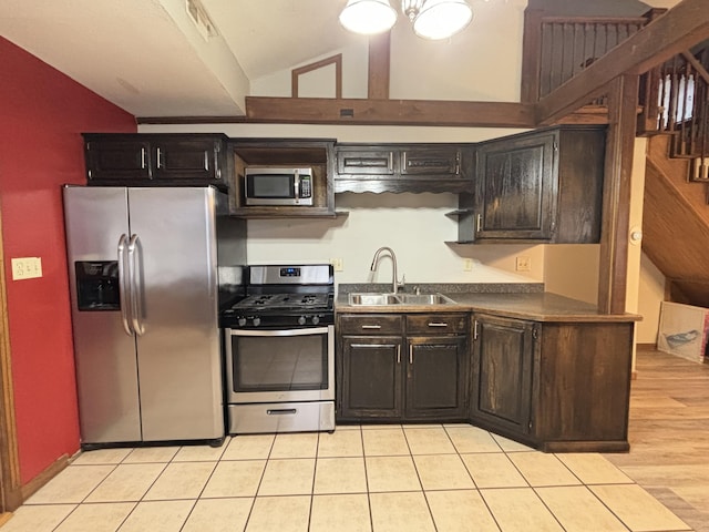 kitchen featuring dark countertops, visible vents, appliances with stainless steel finishes, vaulted ceiling, and a sink