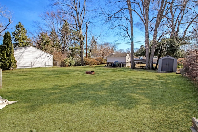 view of yard featuring an outbuilding, a storage unit, and fence