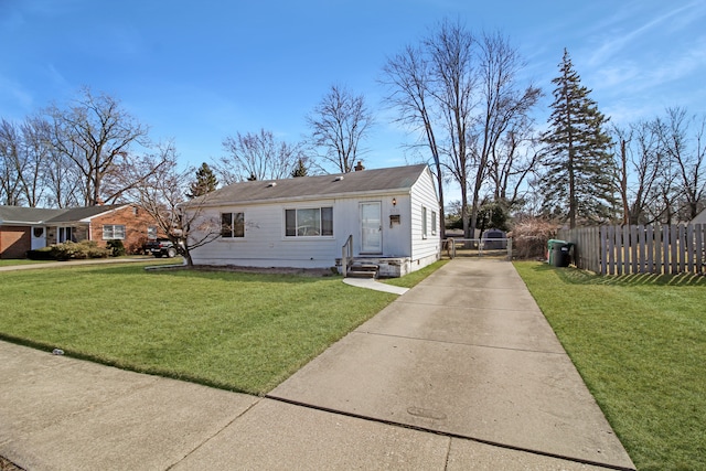 view of front of house with entry steps, driveway, a front yard, and fence