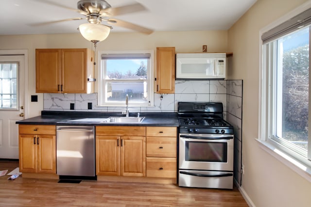 kitchen featuring a sink, plenty of natural light, dark countertops, and appliances with stainless steel finishes