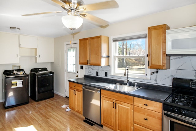 kitchen with dark countertops, washer / dryer, appliances with stainless steel finishes, and a sink