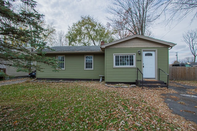 rear view of property featuring fence and a lawn