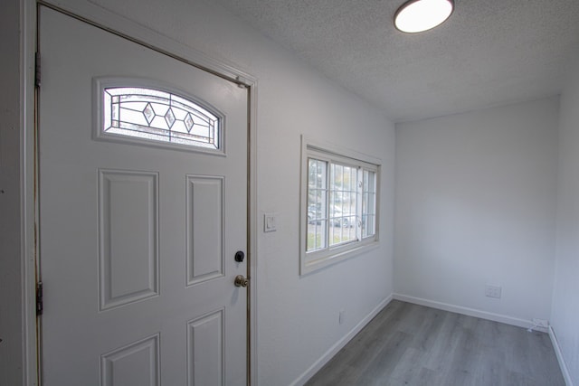 foyer featuring light wood-style floors, baseboards, and a textured ceiling