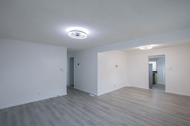 unfurnished room featuring a textured ceiling, wood finished floors, and baseboards