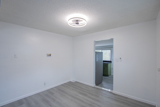 unfurnished room featuring a textured ceiling, baseboards, and wood finished floors