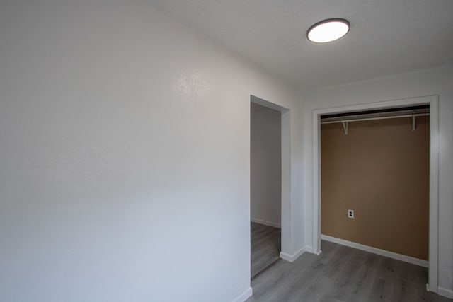 unfurnished bedroom featuring light wood-style floors, a closet, and baseboards