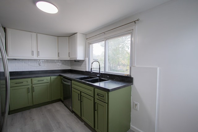 kitchen featuring appliances with stainless steel finishes, dark countertops, a sink, and green cabinets