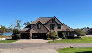 view of front of property with stone siding, driveway, and a front lawn