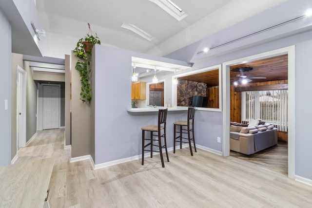 kitchen featuring baseboards, a breakfast bar, light countertops, and light wood-style floors