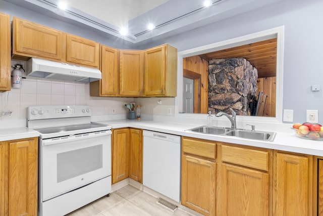 kitchen with white appliances, light countertops, under cabinet range hood, and a sink