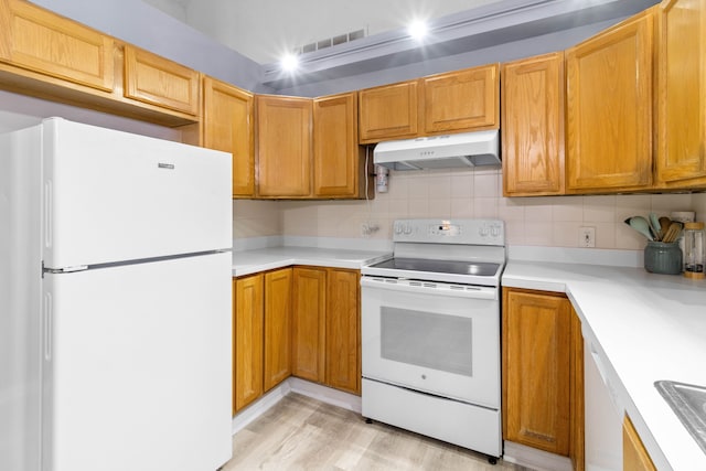 kitchen featuring white appliances, visible vents, light countertops, under cabinet range hood, and tasteful backsplash