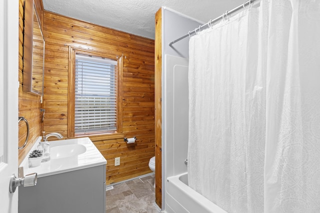 full bath featuring wood walls, a textured ceiling, toilet, and vanity