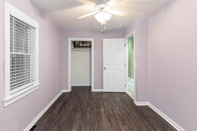 unfurnished bedroom with dark wood-type flooring, baseboards, a closet, and ceiling fan