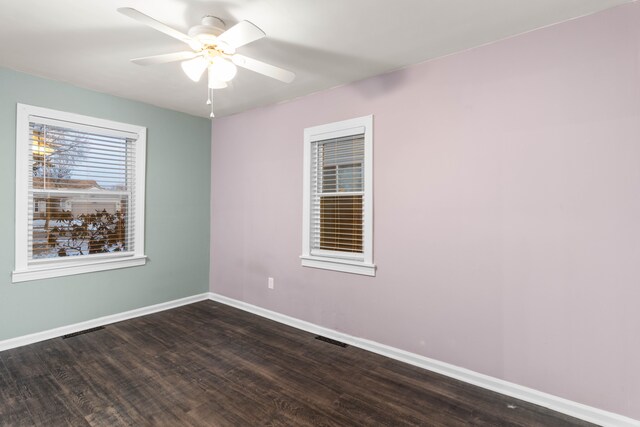 empty room featuring visible vents, a ceiling fan, dark wood-type flooring, and baseboards